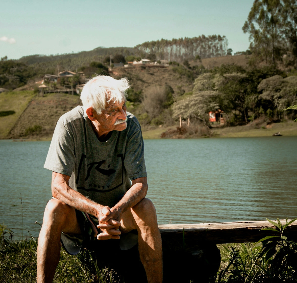 a man sitting on a bench next to a body of water