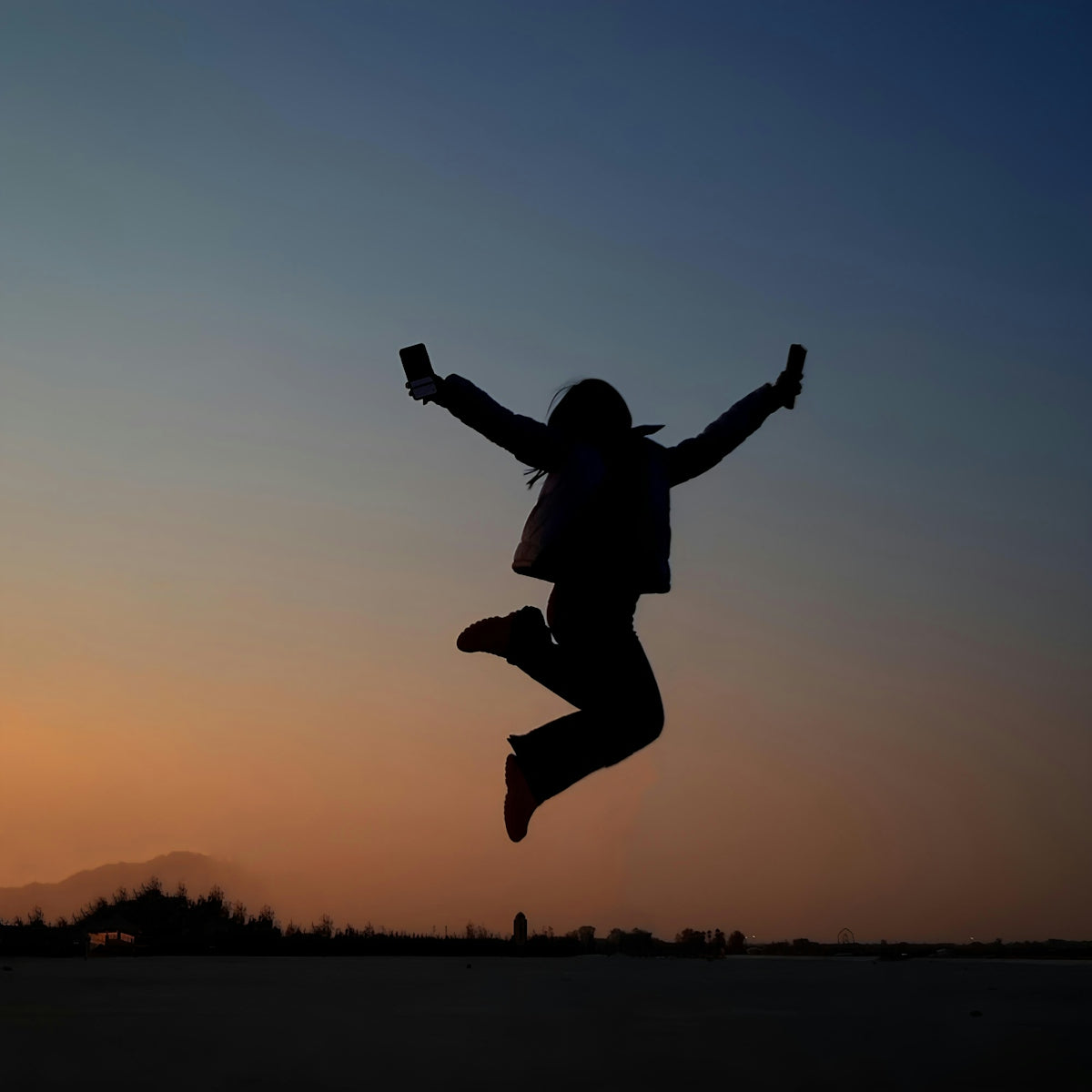 A person jumping in the air at sunset