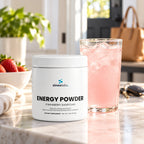 Energy Powder, 200mg Caffeine, Strawberry Shortcake on a bright kitchen counter in morning light beside a tall glass of pale pink drink with ice