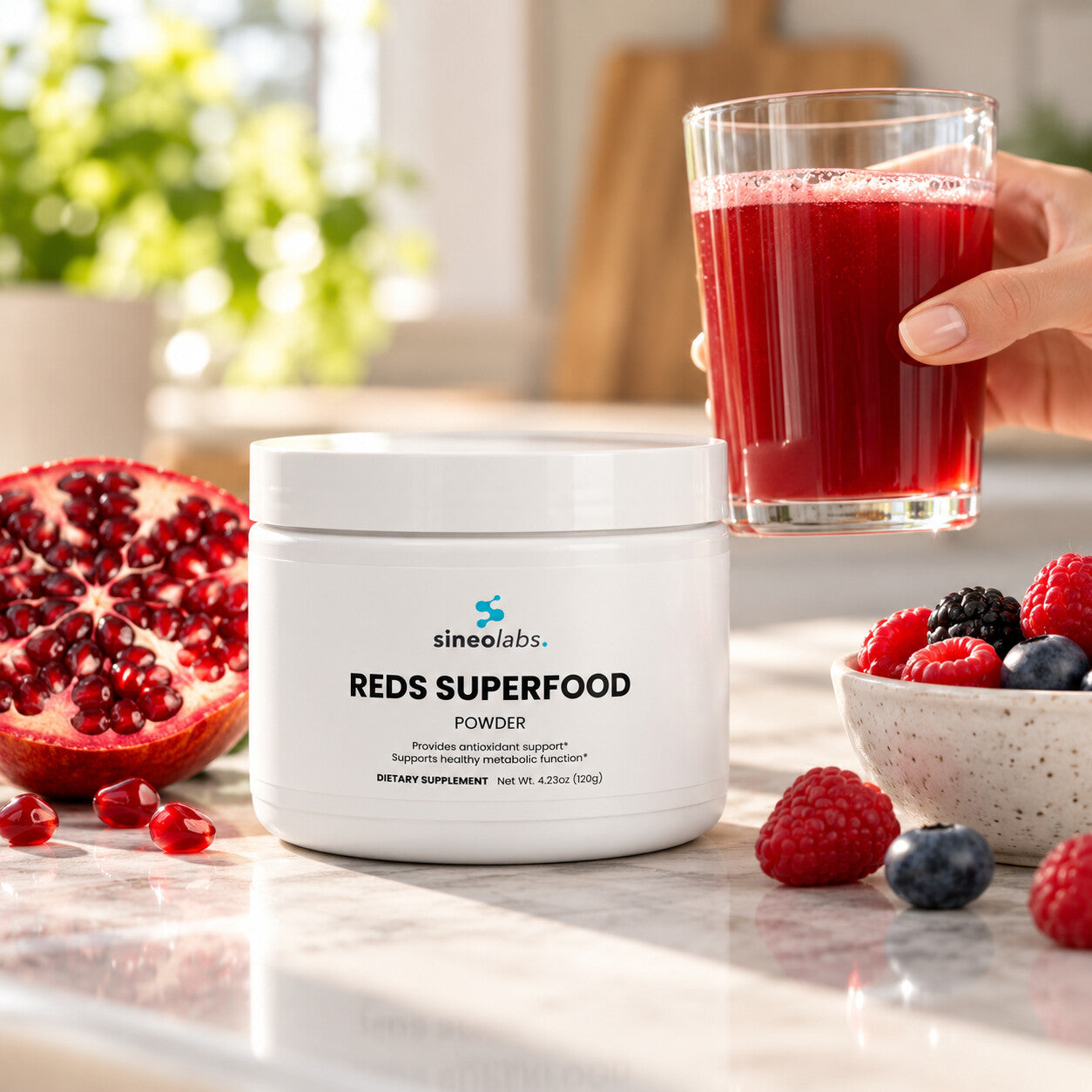 Reds Superfood Powder, 2,000mg Polyphenol Blend on a kitchen counter in bright morning light beside a glass of deep red drink