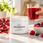Reds Superfood Powder, 2,000mg Polyphenol Blend on a kitchen counter in bright morning light beside a glass of deep red drink